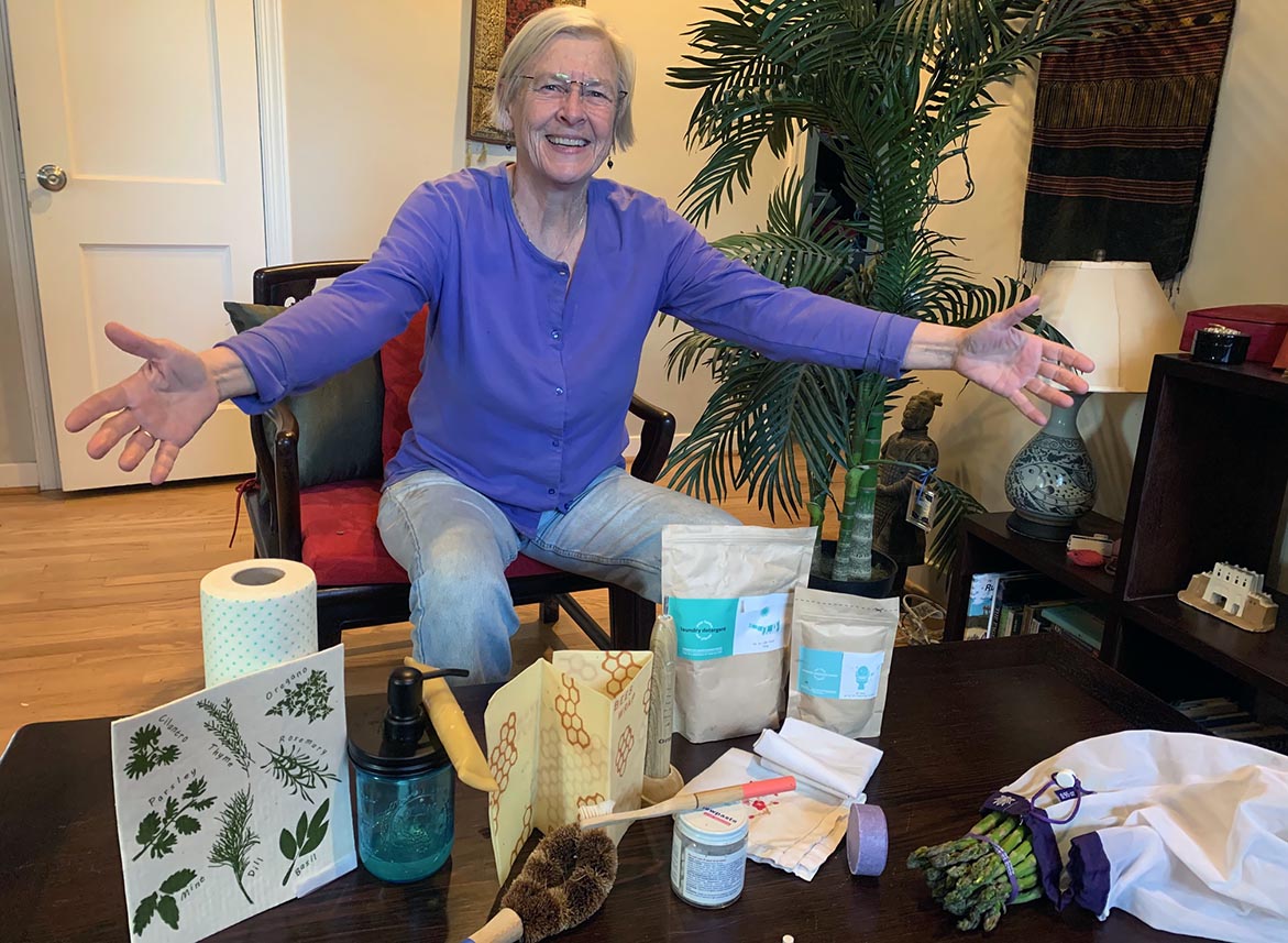 A woman sits infront of a coffee table covered with a variety of products.