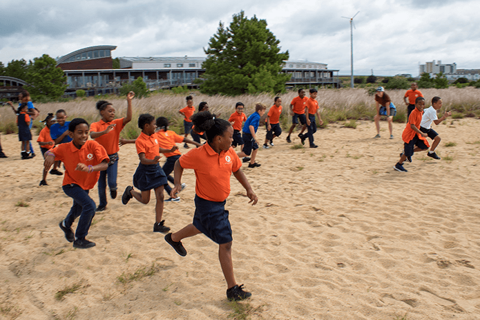 Black youngsters dash across the sandy beach of CBF's Brock Environmental Center.