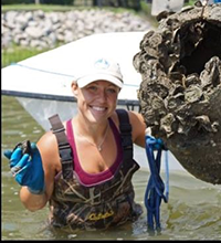 An image of a woman holding an oyster reef ball.