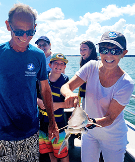 Woman aboard a boat holds a small shark.