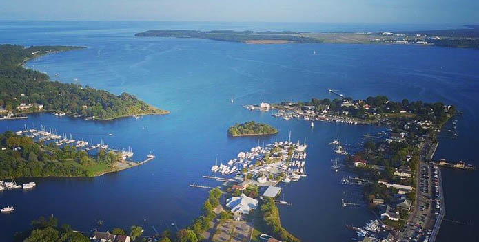 Aerial photo of Solomons Island. The photo looks over the bule of the Bay and the green of the island. 