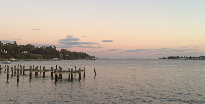 Photo of the Chesapeake Bay with an aging dock in the foreground and a rosy sunset in the background.