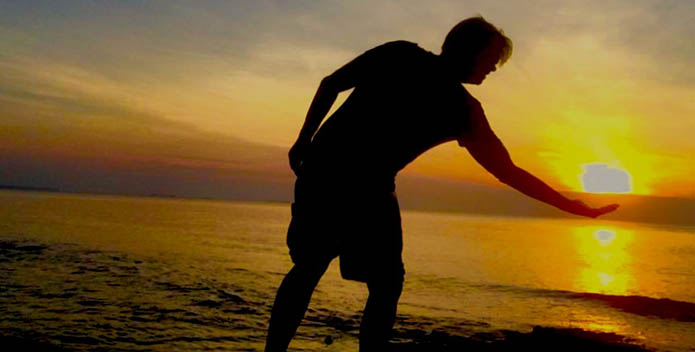 Photo of a man at sunrise looking like he's holding the sun.