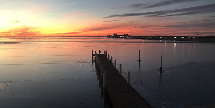 Photo of the Chesapeake Bay at sunset with the Bay Bridge in the background.