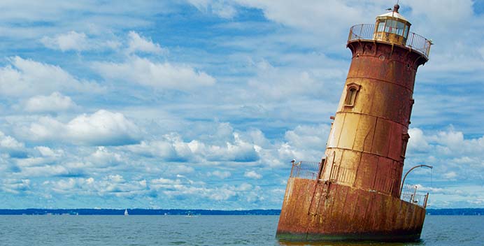 A photo of an abandoned lighhouse rusting in the water.