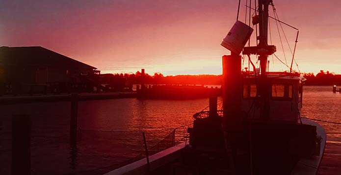 An orge sunrise illuminates the fishing boat 