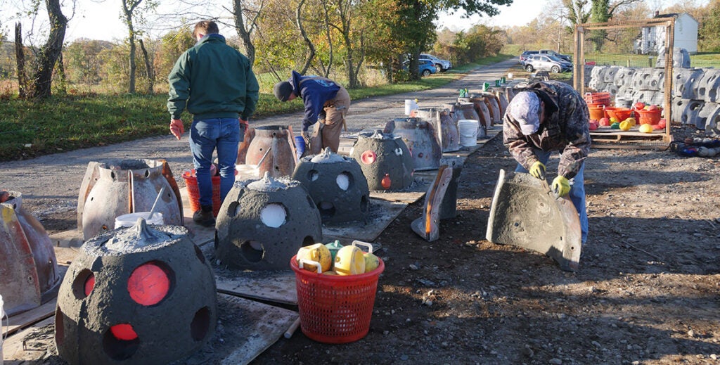 Volunteers use a mold to build reef balls.