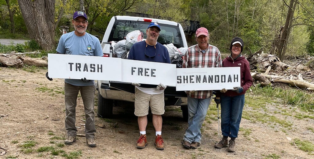 Four people stand in front up a truck holding up a sign that reads, 'trash free Shenandoah.'