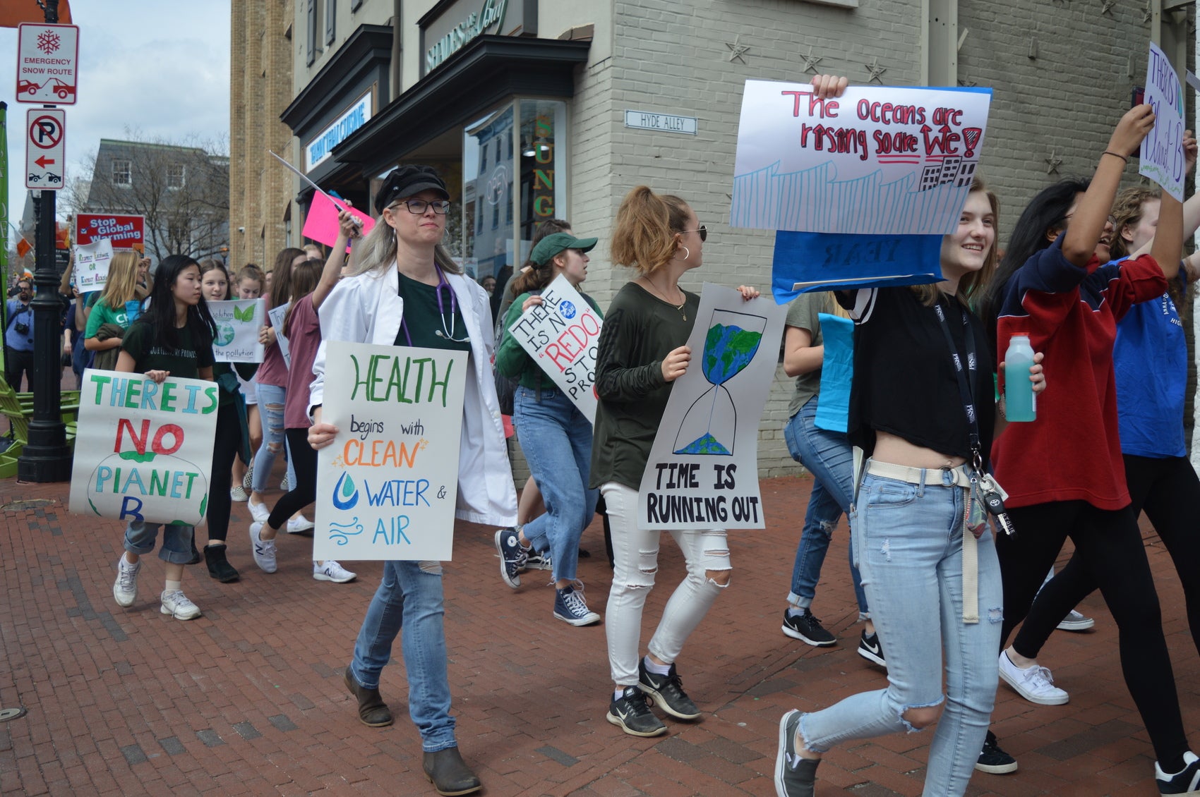 Students walking down the street in protest as part of the Youth Climate Strike, holding a variety of signs