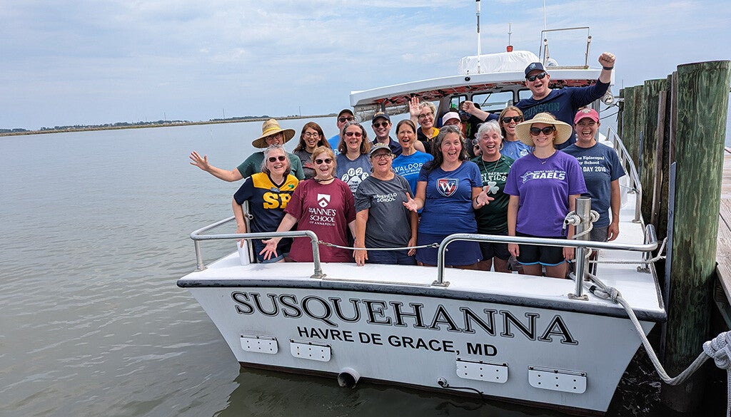 A cheerful group of educators beams and waves aboard the Susquehanna docked in Havre de Grace, MD.