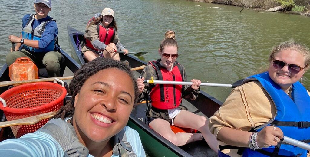 Students from the Bay Advocacy Institute paddle canoes on a sunny day, enjoying hands-on environmental education on a calm river.
