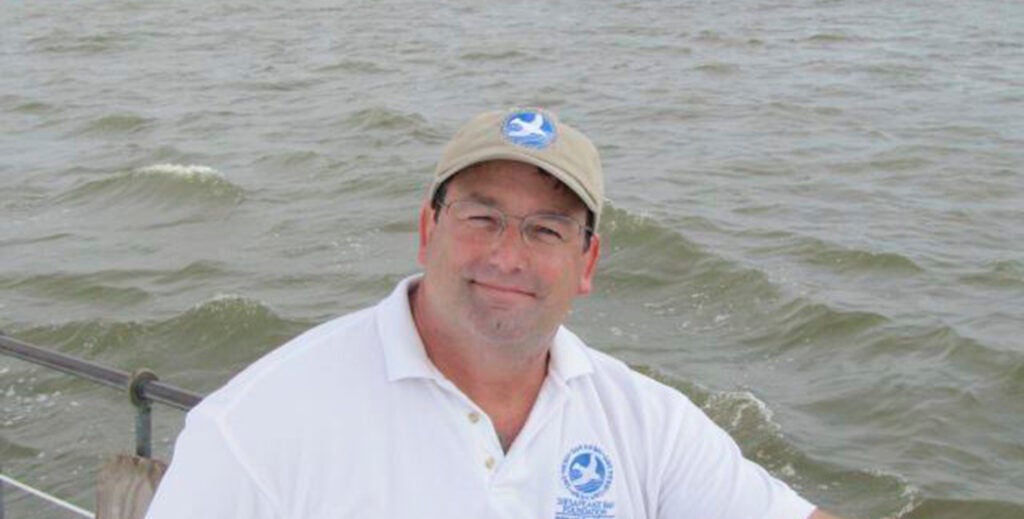 A man wearing a Chesapeake Bay Foundation hat and shirt smiles at the camera.