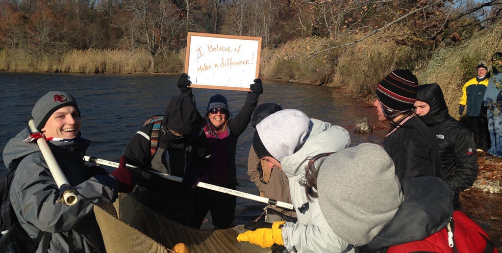 Education staff out with students hold a sign reading "I believe it makes a difference."