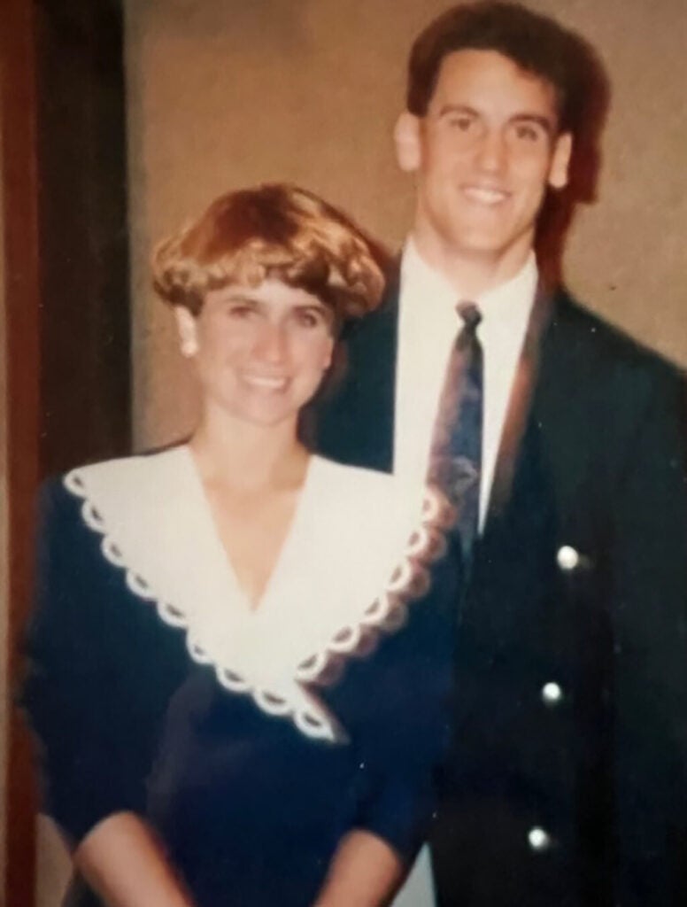 A smiling young couple stand next to each other.