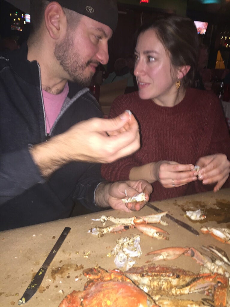 A man and woman look at each other while picking crabs.