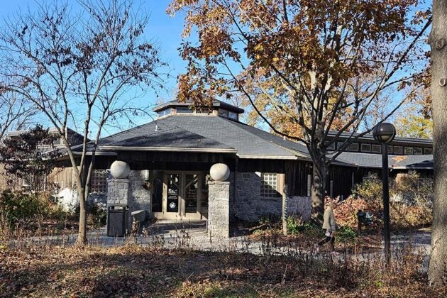 The Wildwood Olewine Nature Center building with stone pillars, surrounded by trees with autumn foliage.