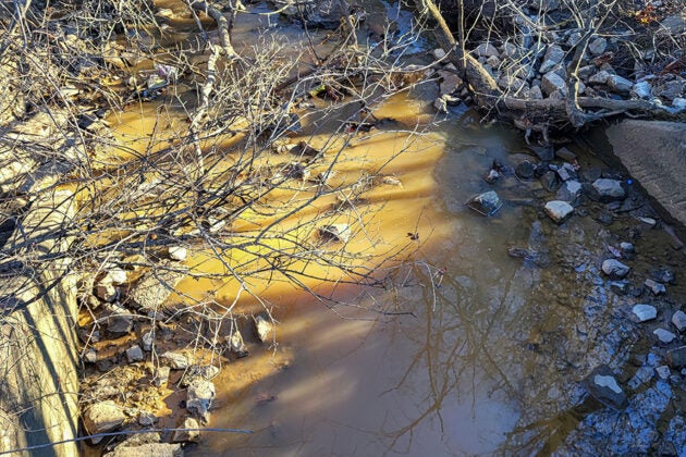 Yellow-orange runoff water flows into a creek