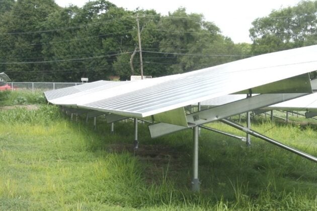 Solar panel arrays mounted on metal frames in a grassy field.