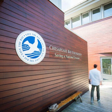 A man walks past a wood wall bearing the Chesapeake Bay Foundation logo on his way to the front doofs.