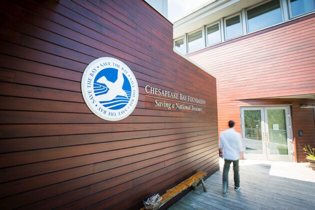 A man walks past a wood wall bearing the Chesapeake Bay Foundation logo on his way to the front doofs.