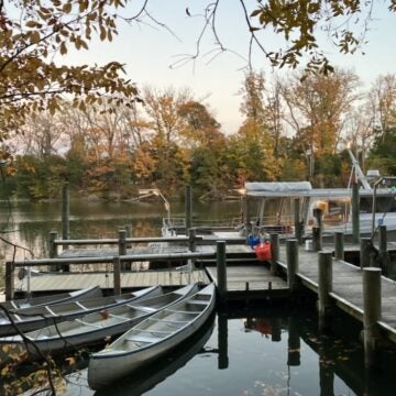 Four canoes and an education boat sit at the end of a pier.