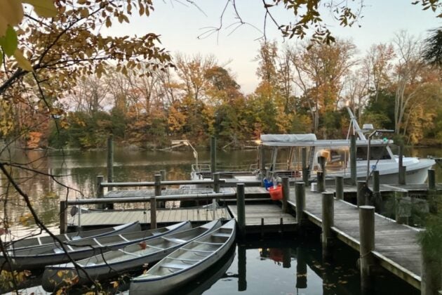 Four canoes and an education boat sit at the end of a pier.