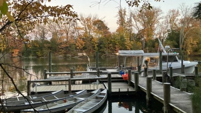 Four canoes and an education boat sit at the end of a pier.