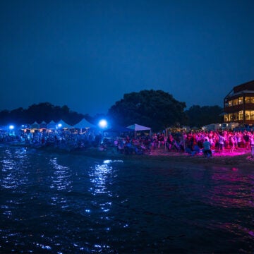 Evening beach party and stage. Text reads 20 Years - Annapolis Subaru proudly sponsors Bands in the Sand.