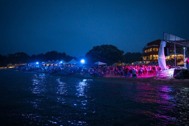 Evening beach party and stage. Text reads 20 Years - Annapolis Subaru proudly sponsors Bands in the Sand.