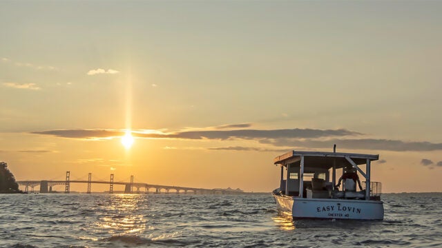 A crabbing boat approaches the Chesapeake Bay Bridge at sunrise.