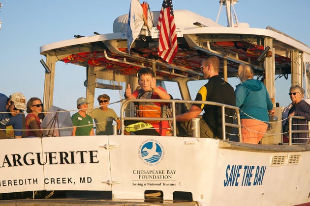 A young boy gives a thumbs up amid a crows of people enjoying a ride on the CBF vessel Marguerite.