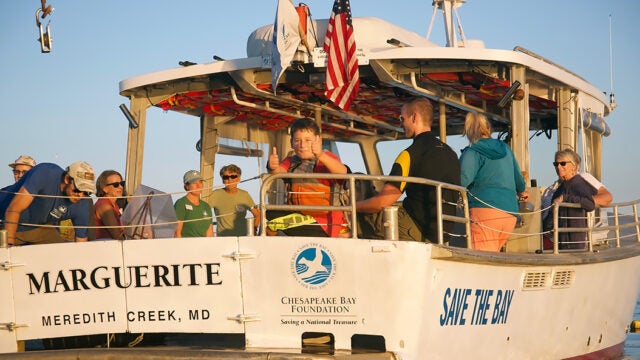 A young boy gives a thumbs up amid a crows of people enjoying a ride on the CBF vessel Marguerite.