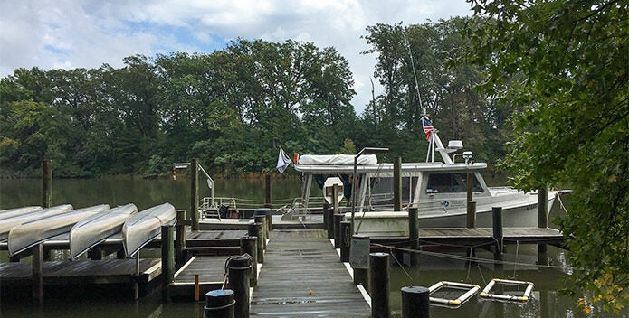 A CBF education vessel and a row of canoes sit at the end of a pier.