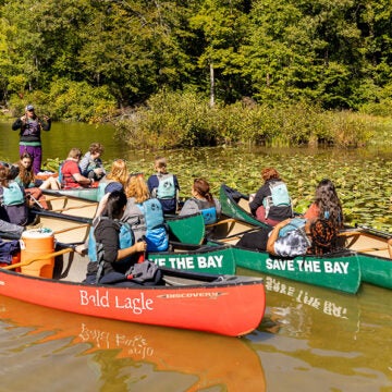 Students in canoes gather to listen to an instructor.