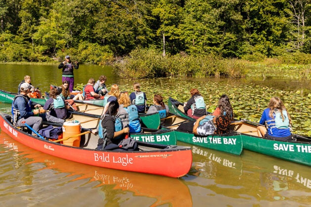 Students in canoes gather to listen to an instructor.