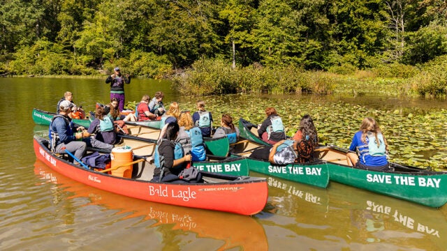 Students in canoes gather to listen to an instructor.