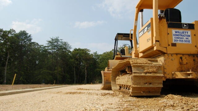 A bulldozer surrounded by dirt, with trees in the distance.