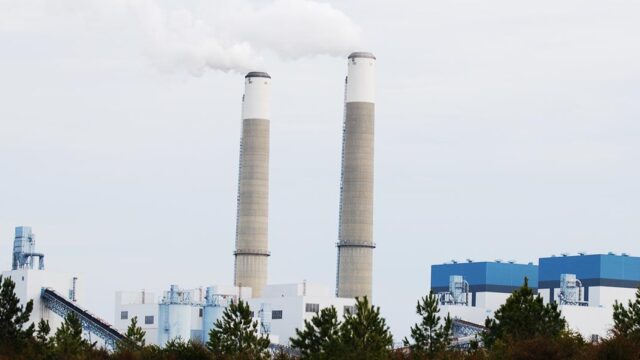 The Clover Power Station in Virginia with two tall smokestacks releasing steam above the industrial facility.