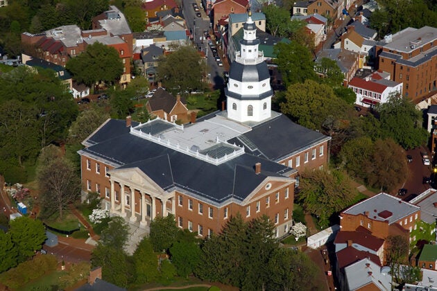 Aerial view of the Maryland State House with its white dome, surrounded by historic Annapolis buildings and green trees.