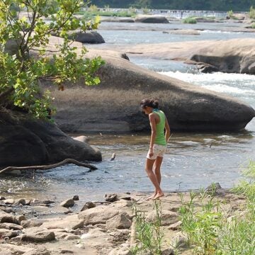 Two children play along the rocks next to the James River