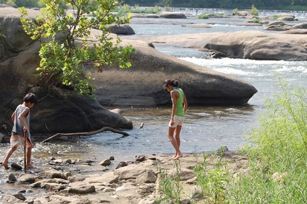 Two children play along the rocks next to the James River