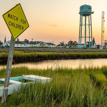 The sun rises behind a coastal town.