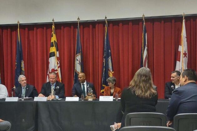 Gov. Wes Moore sits at a long table with other officials.