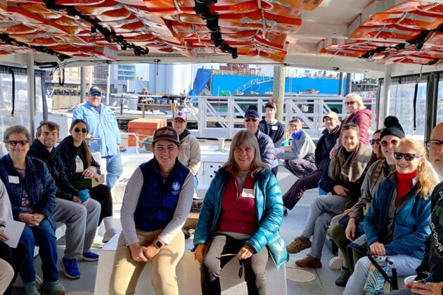 A group of people sit aboard a boat docked in the Baltimore Inner Harbor